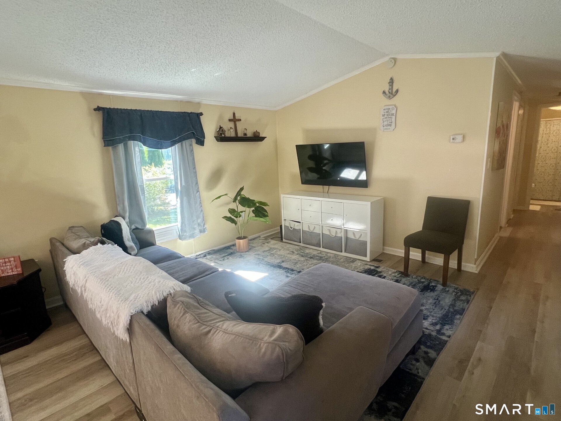 Living room with a large sectional sofa, patterned rug, and wall-mounted television.