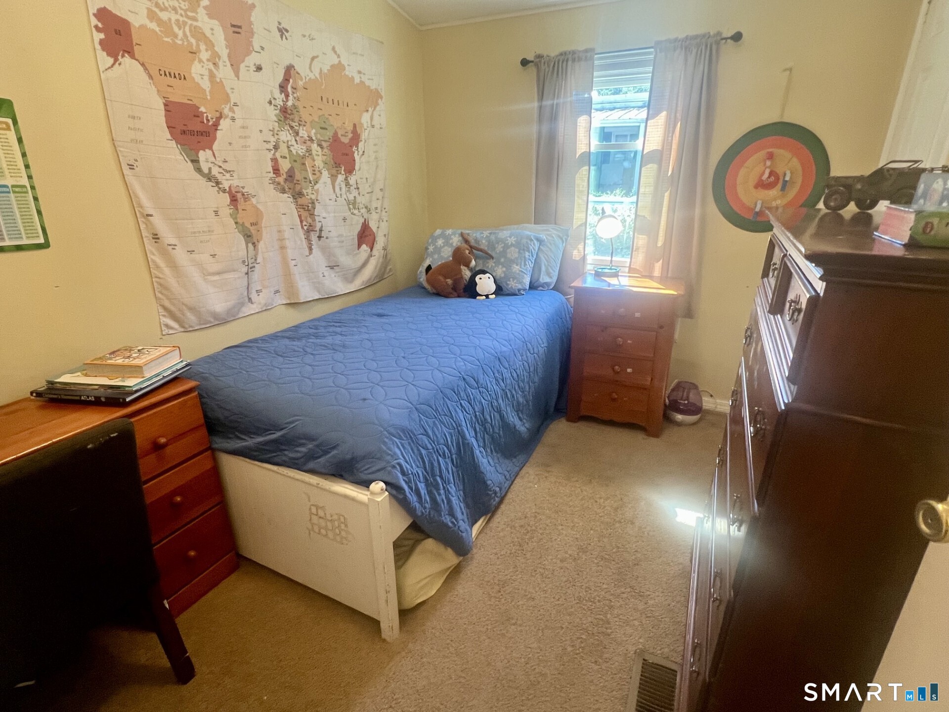 Bedroom with a blue-covered single bed beneath a large world map.