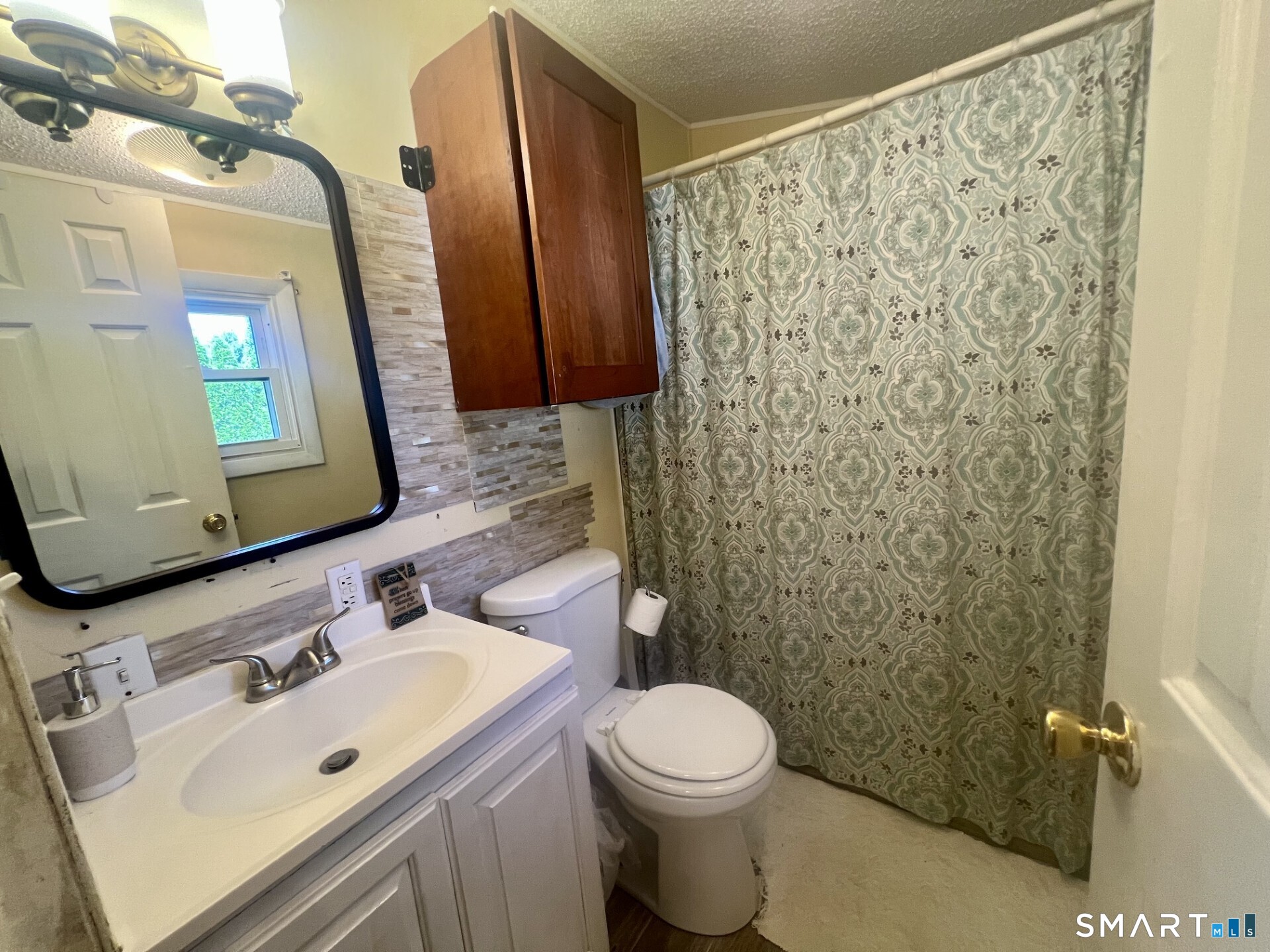 Bathroom with a white vanity, dark wood wall cabinet, and patterned shower curtain.