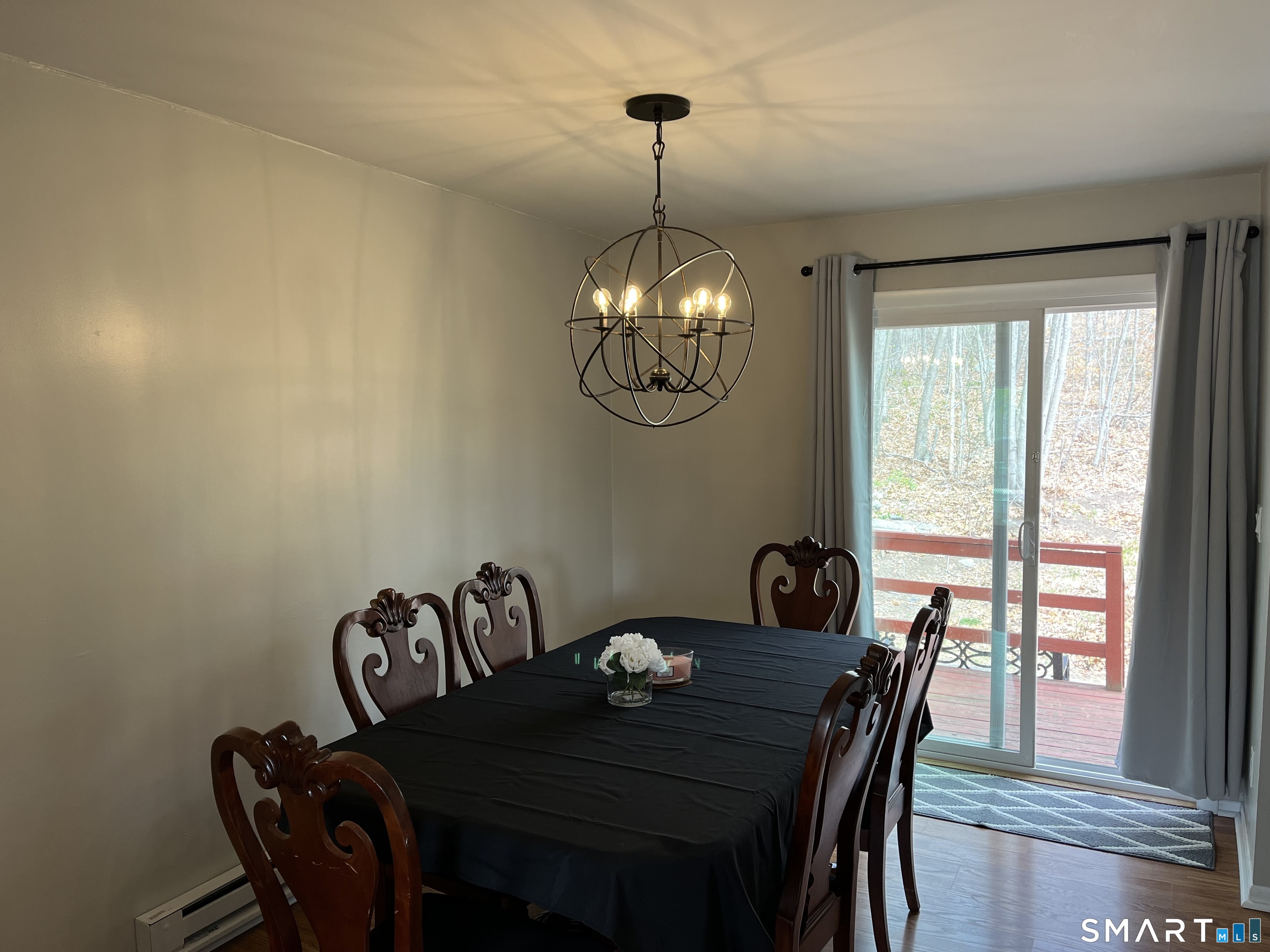 Dining room with ornate wooden chairs, a spherical chandelier, and sliding doors to a deck.