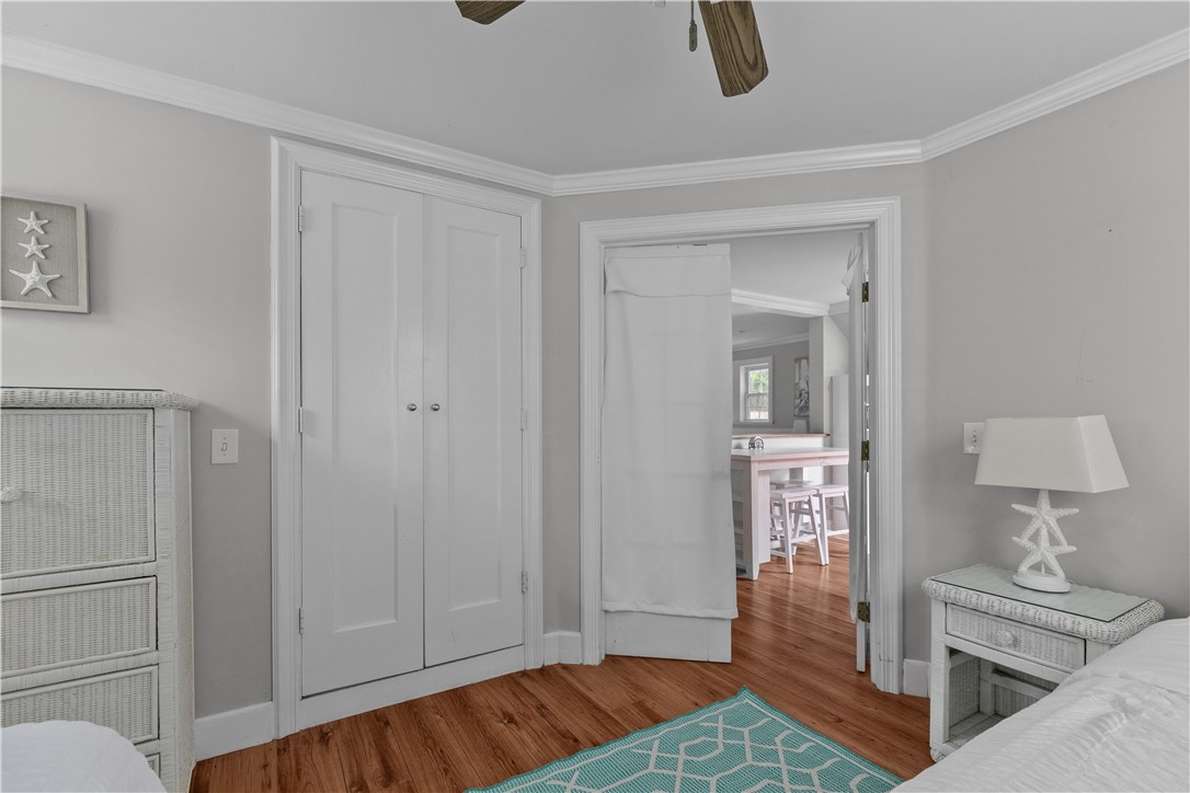 Bedroom with a white double-door closet, hardwood floors, and a turquoise rug beside an open doorway.