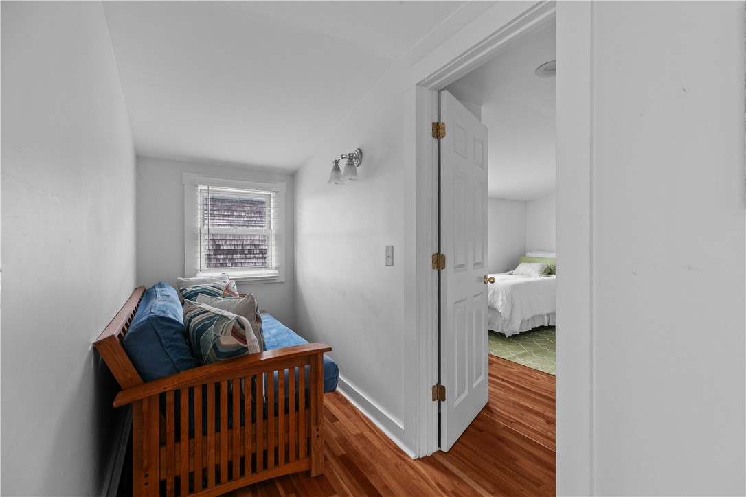 Narrow sitting nook with a wooden daybed and blue cushions beside an open bedroom doorway.