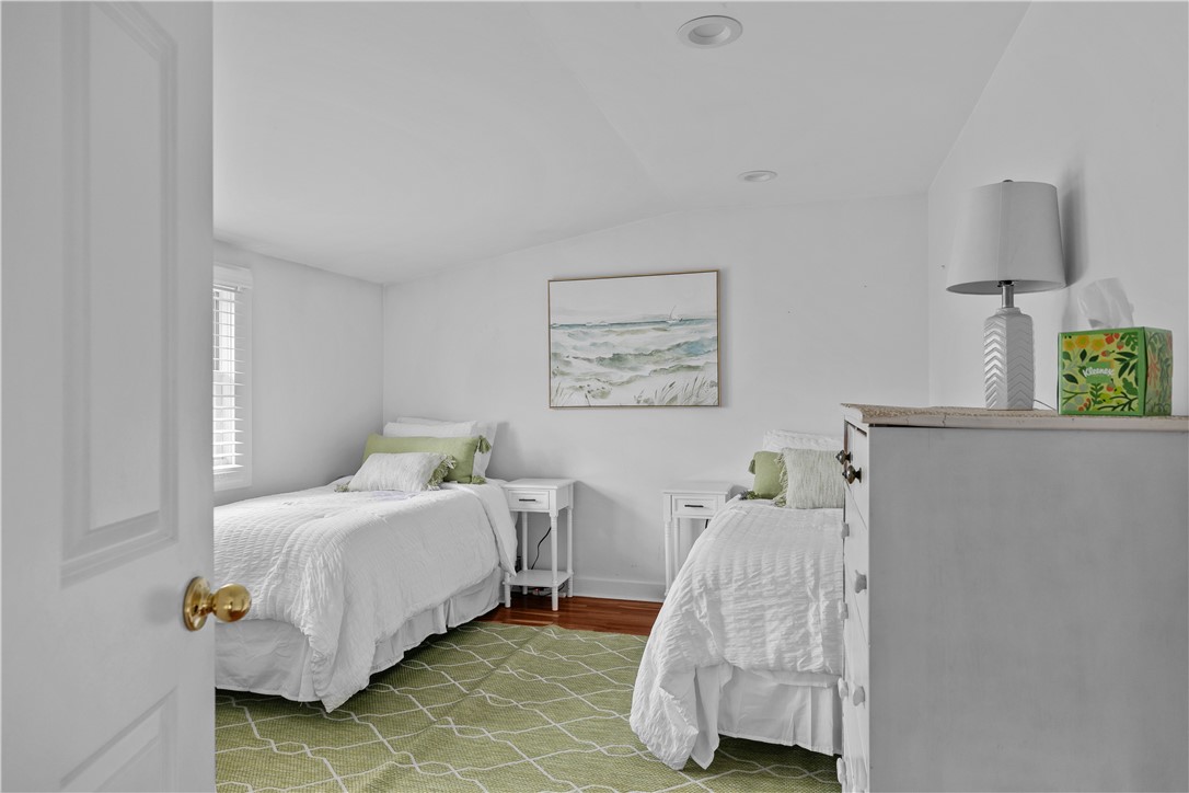 Bedroom with two white single beds, green accents, and a seascape print.