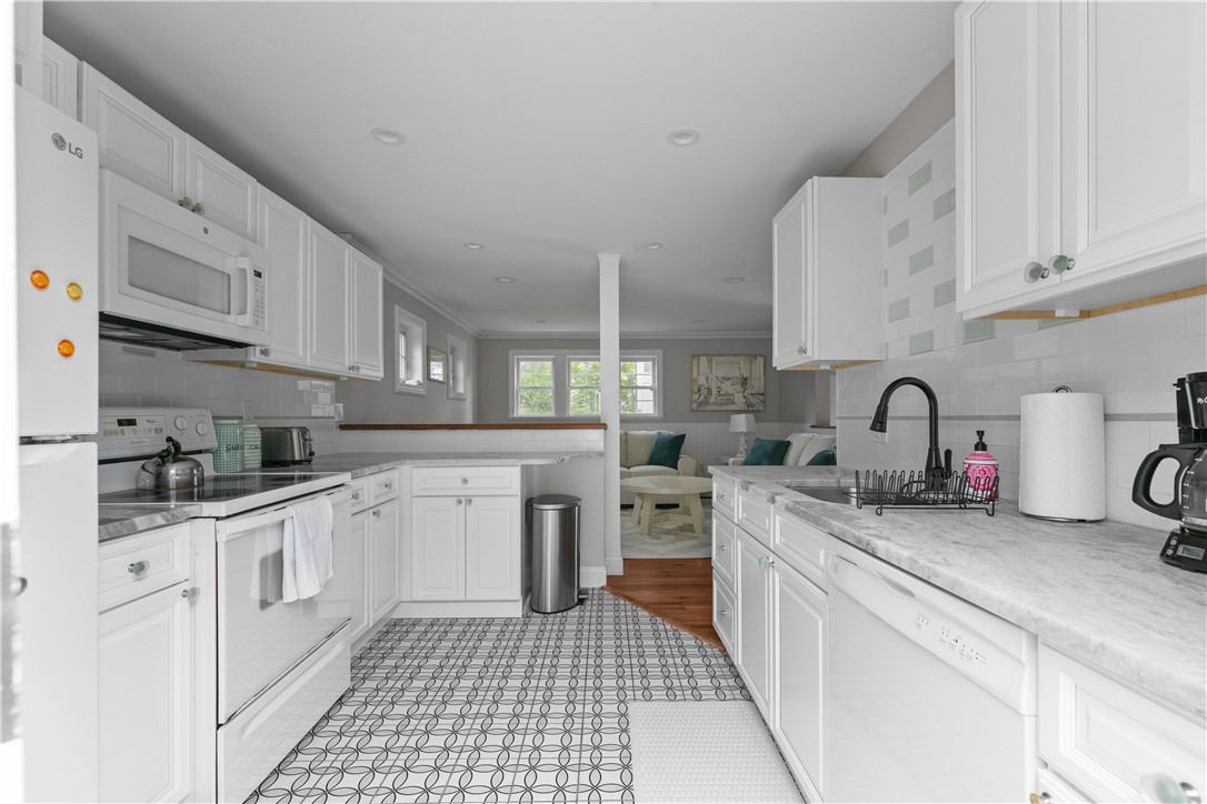 White kitchen with patterned tile floors, marble-look counters, and a view into the living room.