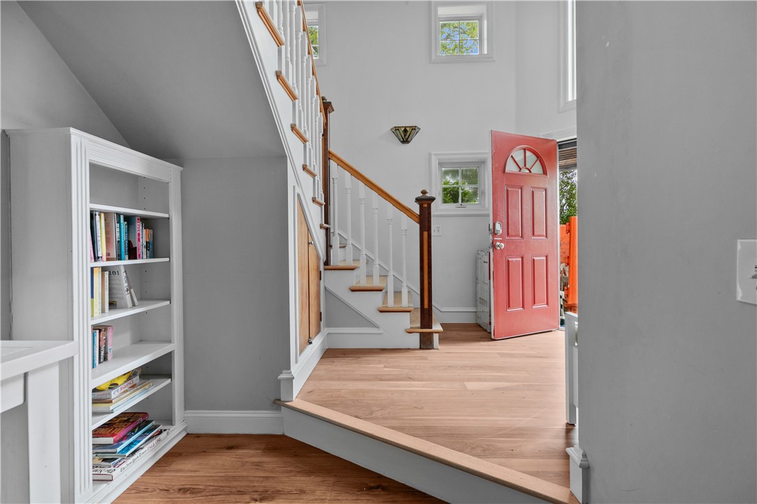 Entryway with an open red door, white staircase, wood handrails, and built-in bookshelf.