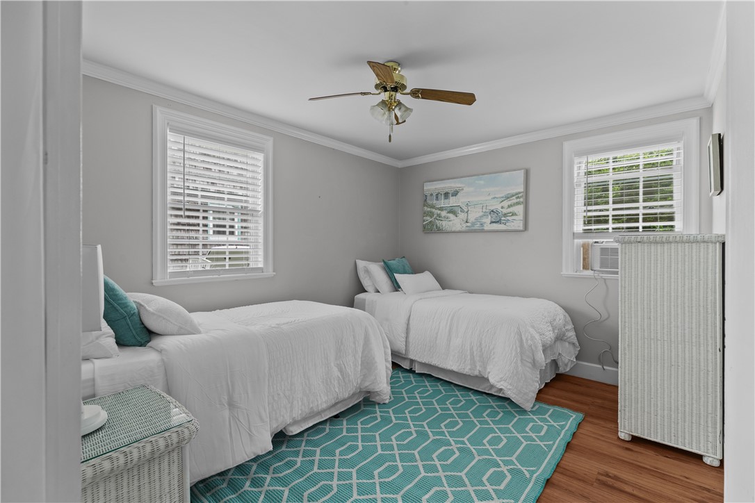 Bedroom with two white beds, teal accents, and a turquoise geometric rug.