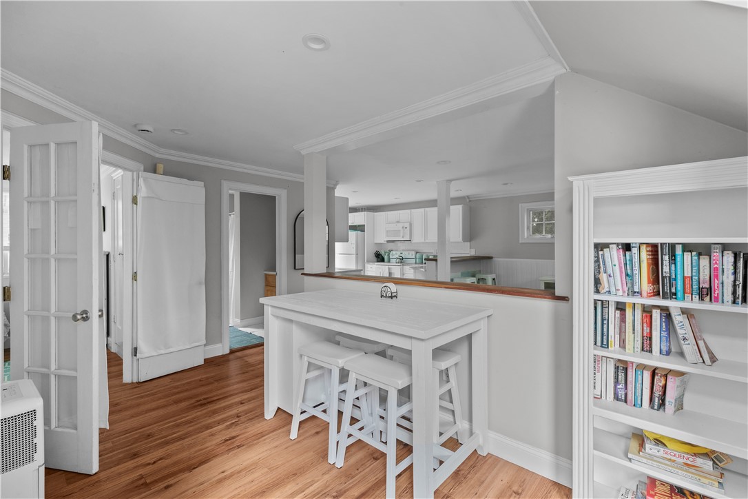 Open-plan kitchen with a white island, stools, hardwood floors, and a built-in bookcase.