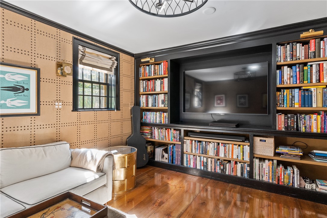 Media room with built-in bookcases around a large TV, a white sofa, and hardwood floors.
