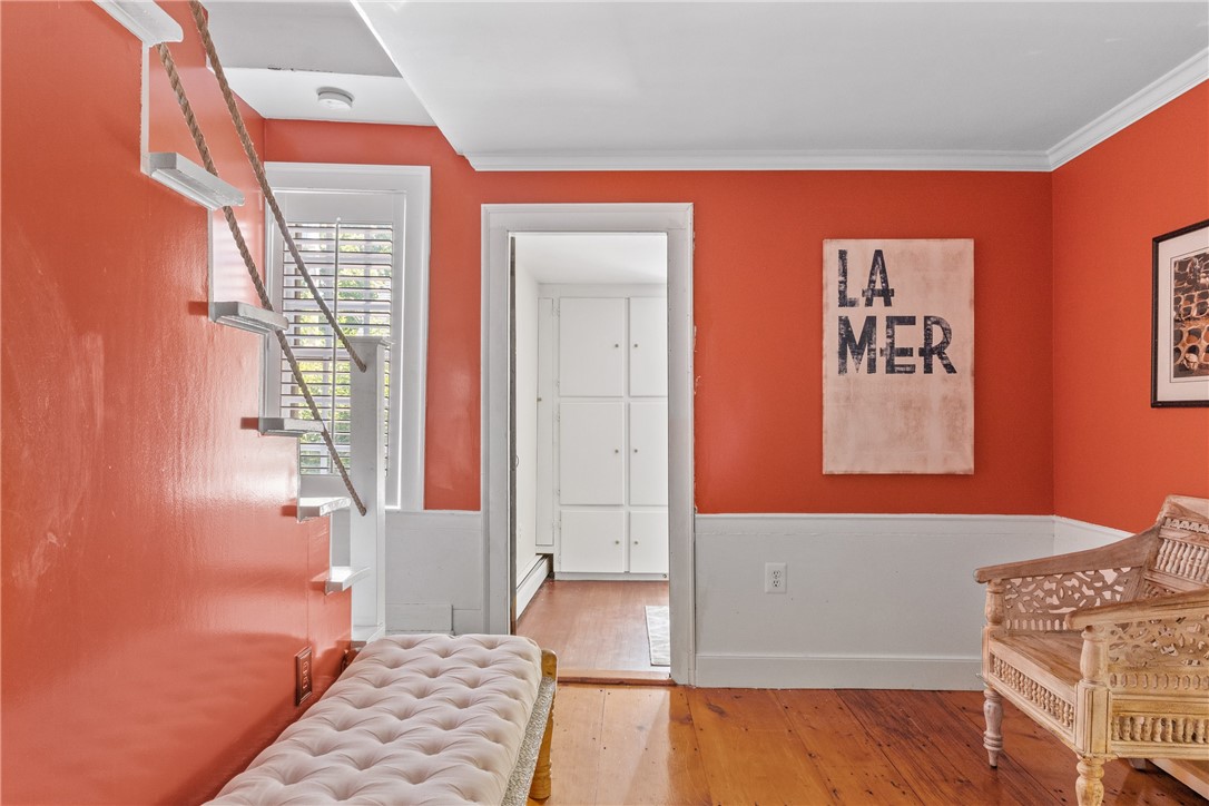 Sitting area with coral walls, a floating staircase, tufted bench, and carved wicker chair.