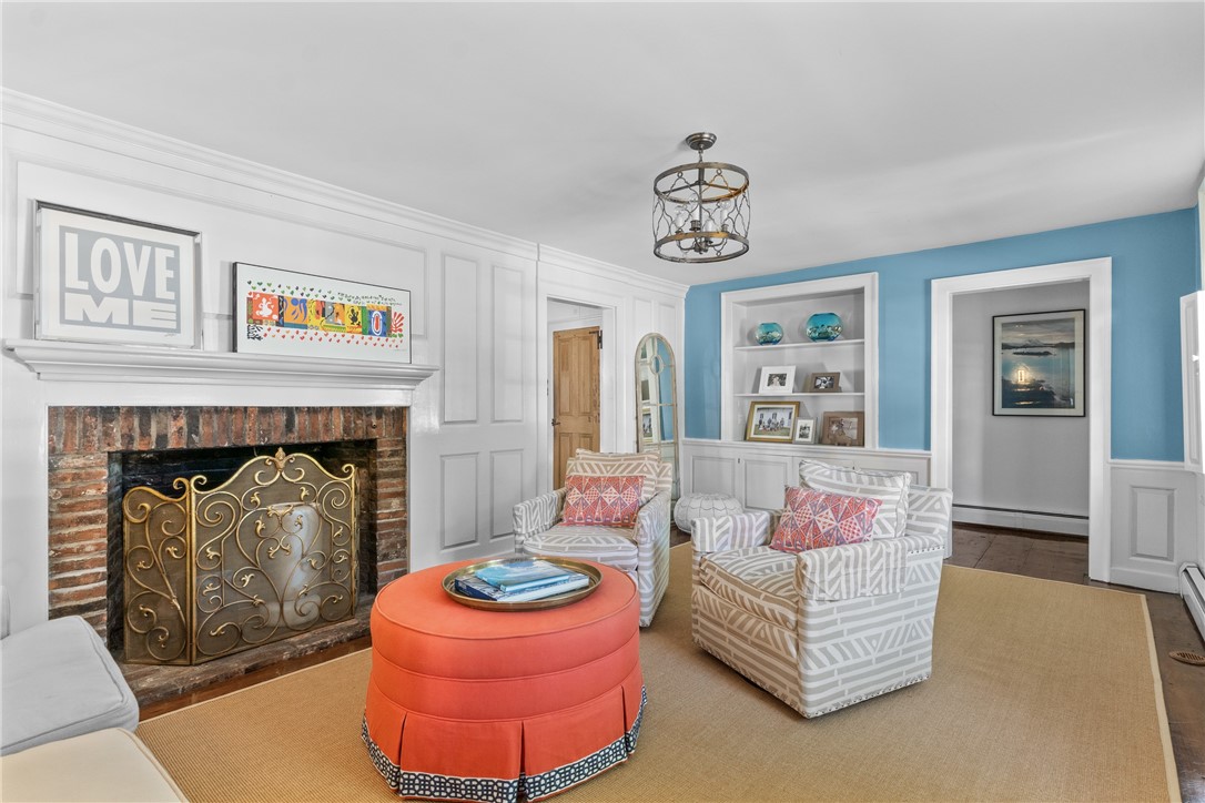 Living room with a brick fireplace, blue accent wall, patterned armchairs, and round orange ottoman.