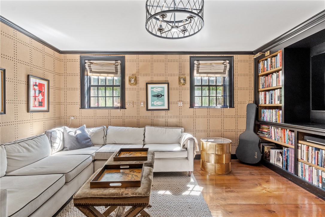 Living room with a white sectional, patterned walls, hardwood floors, and a built-in bookcase.