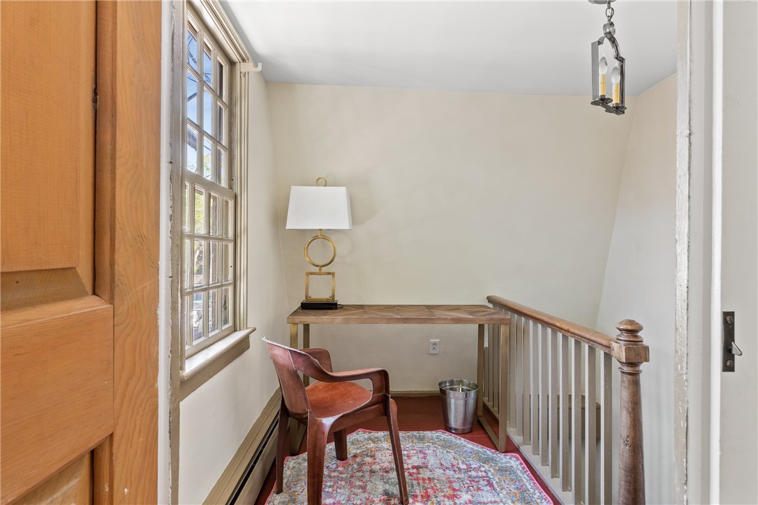 Landing with a desk and brass lamp beside a tall window, leather chair, and staircase railing.