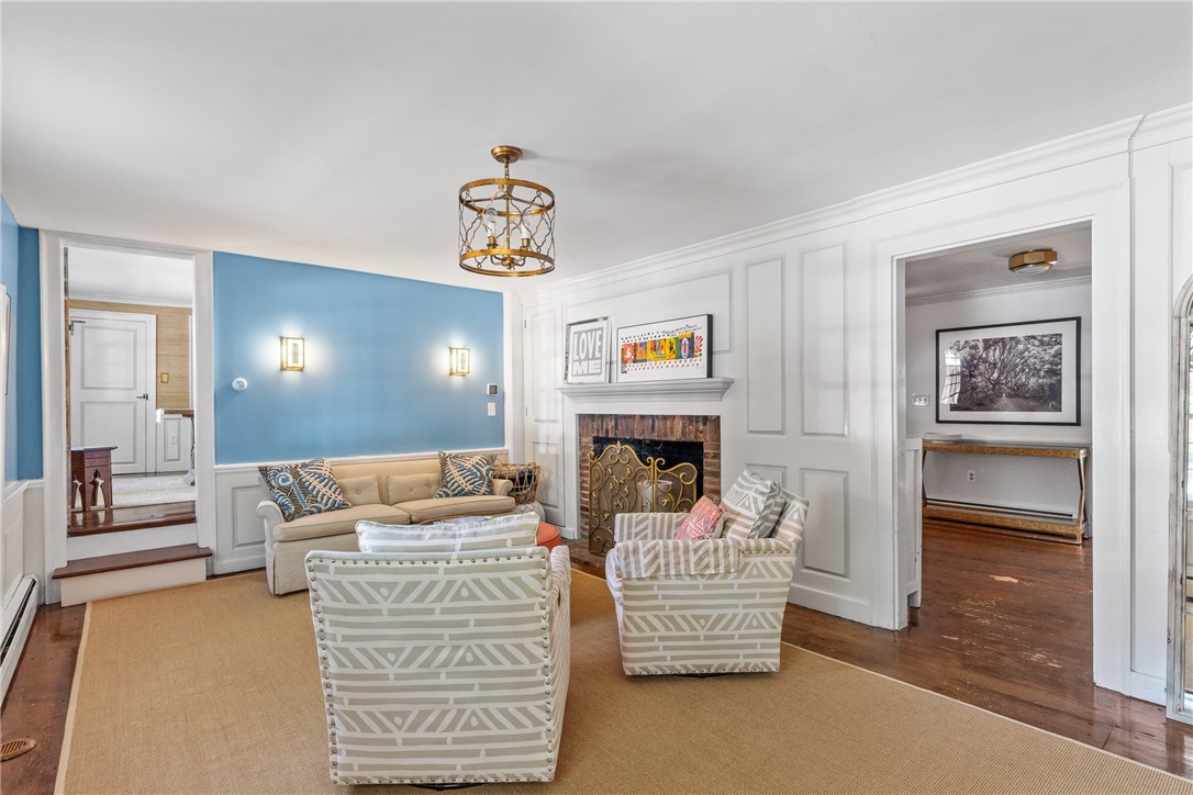 Furnished living room with a blue accent wall, ornate fireplace, and patterned armchairs.
