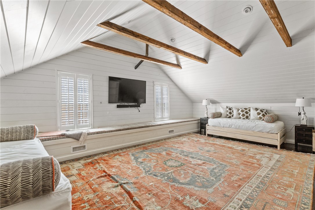 Attic bedroom with exposed timber beams, two beds, and a built-in window seat.