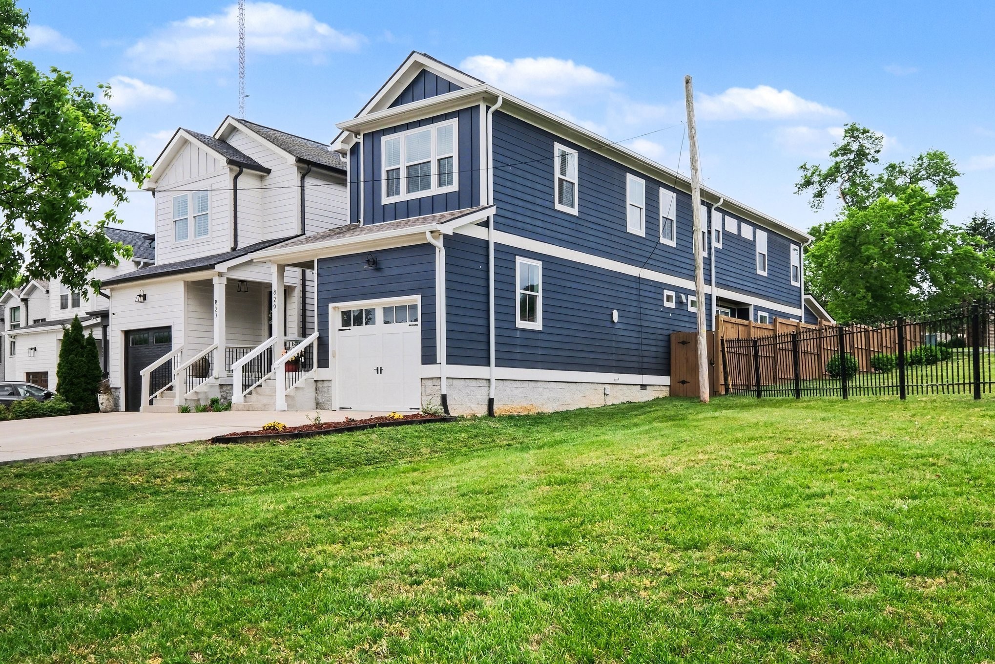 Two-story navy-blue home with white trim, a covered entry, garage, and broad front lawn.