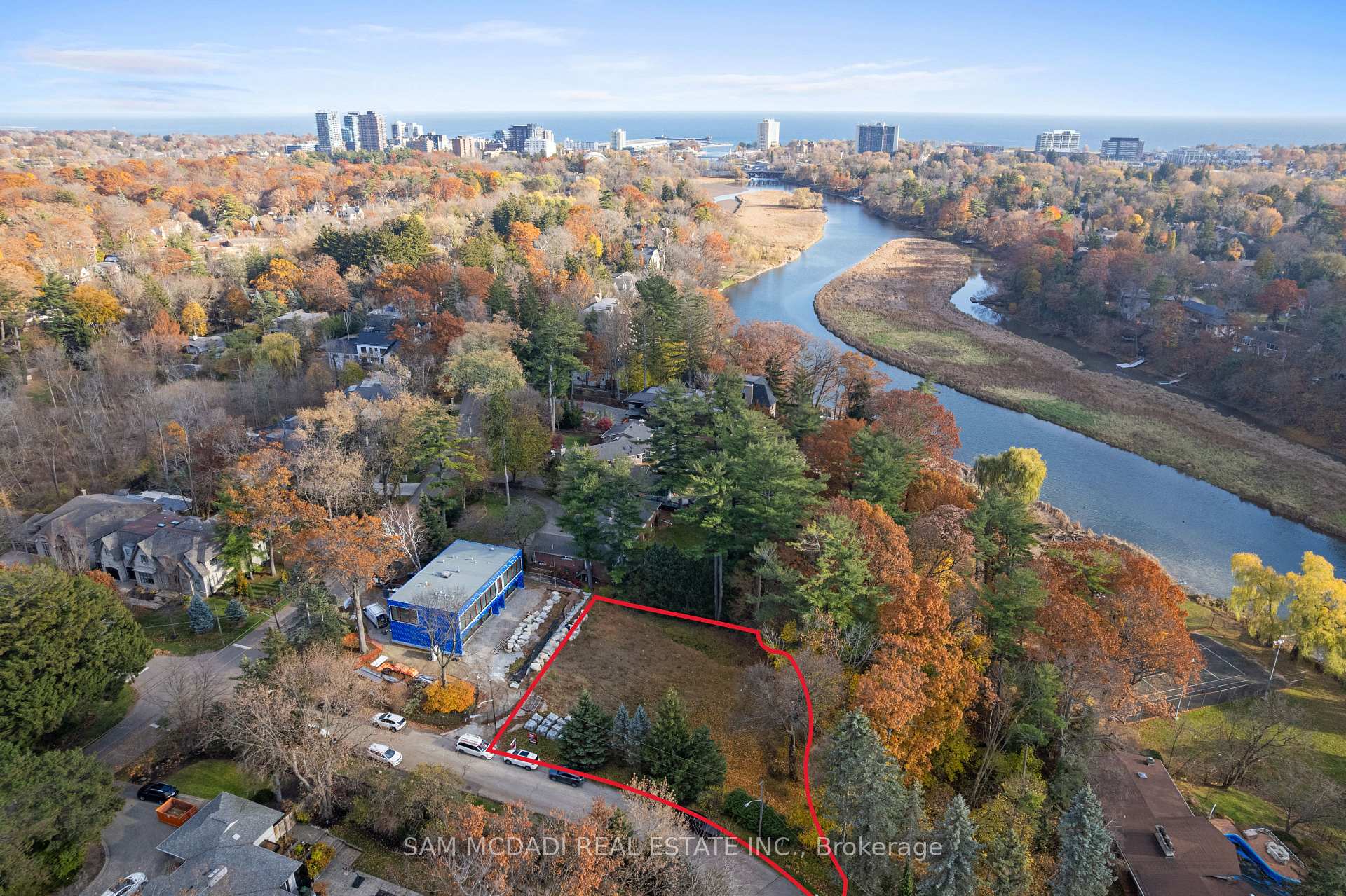 Aerial view of a vacant lot outlined in red beside a winding river and autumn trees.