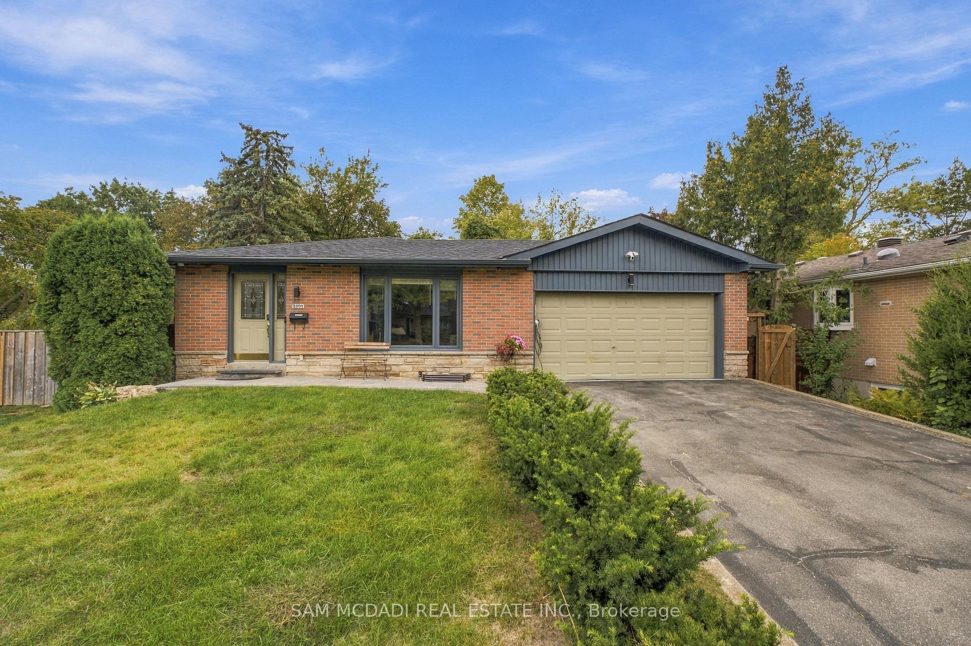 Single-story brick house with gray siding, a two-car garage, and a broad front lawn.