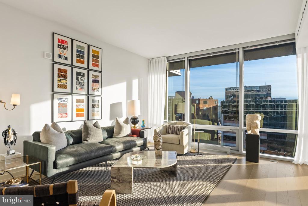 Living room with floor-to-ceiling windows overlooking city buildings.