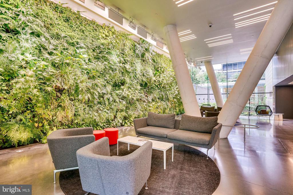 Building lobby lounge with a living green wall, gray seating, and angled columns.