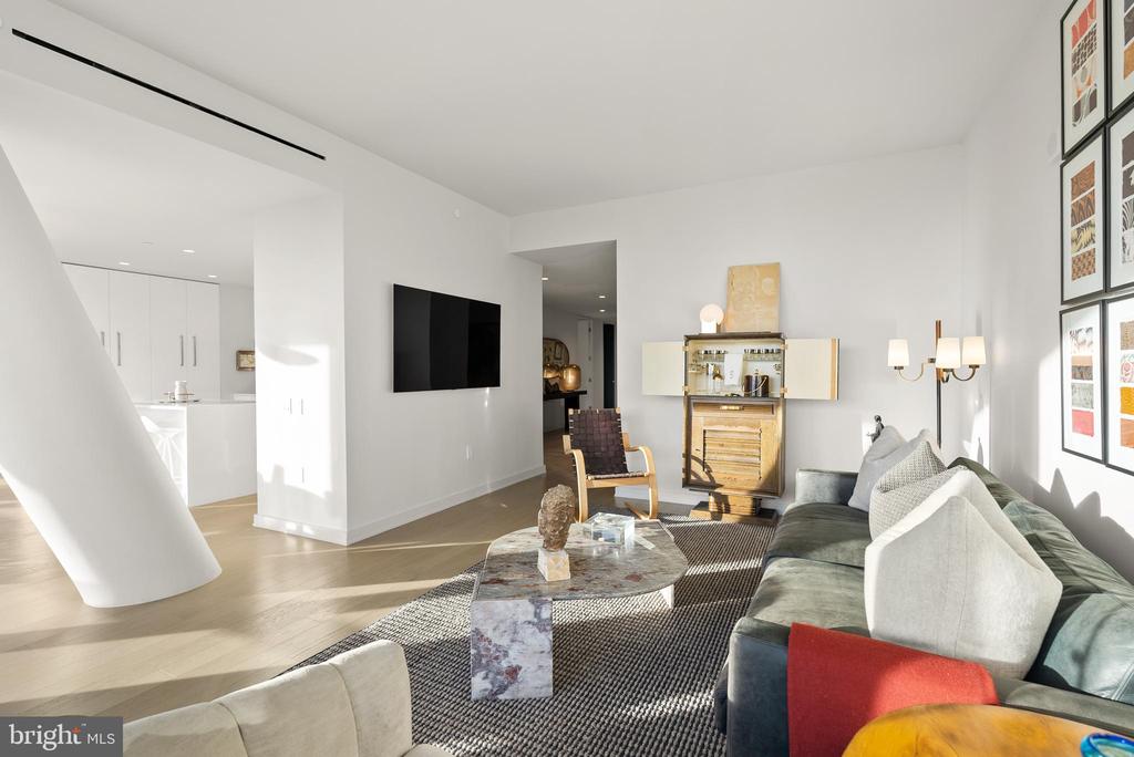 Living room with a green sectional, stone coffee table, and open kitchen.