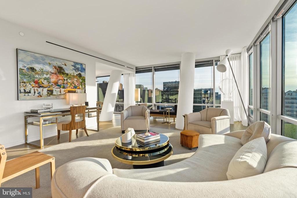 Bright condo living room with curved white sofas and floor-to-ceiling windows overlooking the city.