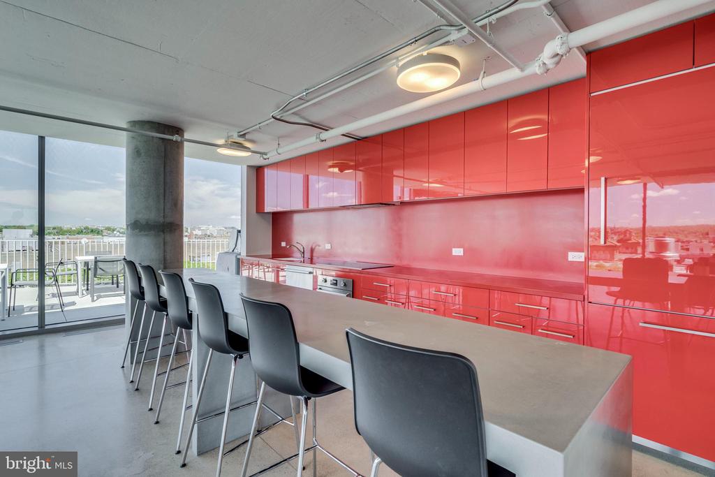 Modern kitchen with glossy red cabinets, a long island, and windows opening onto a balcony.
