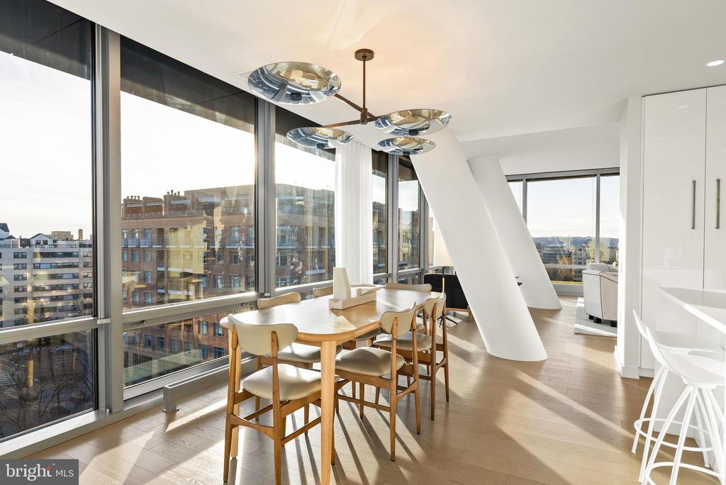 Modern dining area with floor-to-ceiling windows overlooking city buildings.