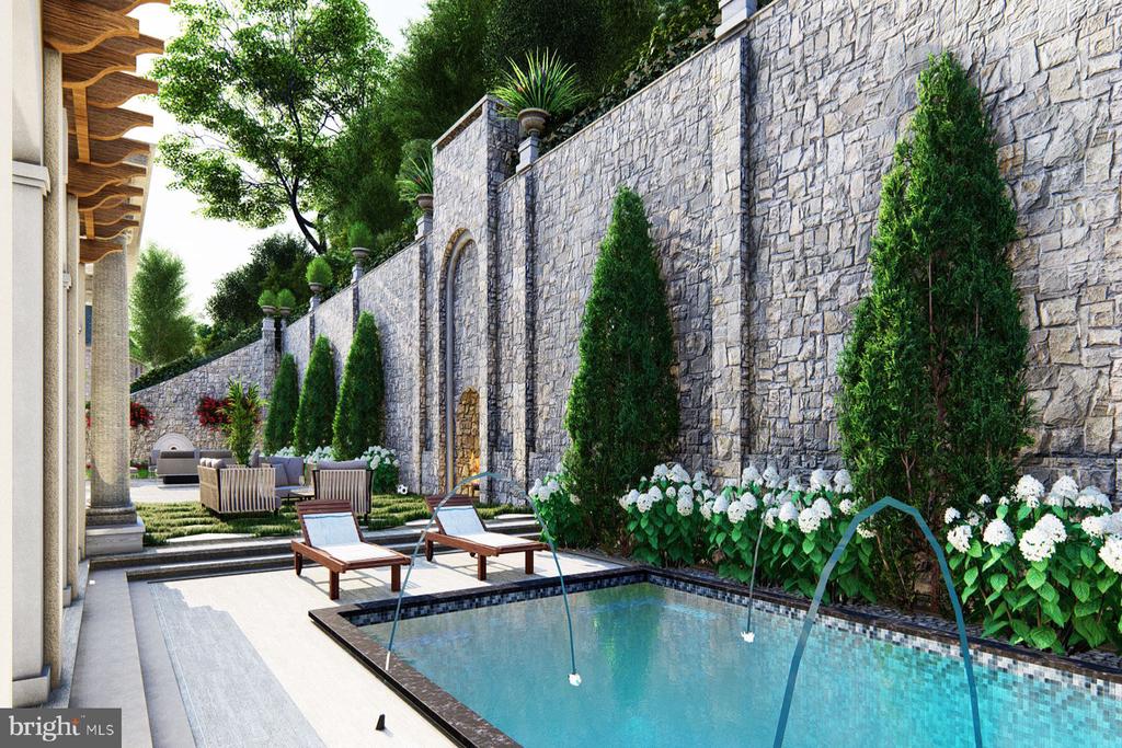 Outdoor pool beside a tall stone wall, with lounge chairs and flowering plants.