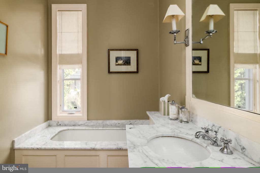 Bathroom with a built-in tub, marble vanity, oval sink, and large mirror.