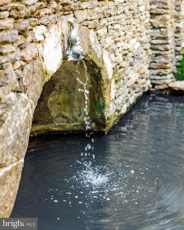 Stone wall fountain trickling into a dark basin.
