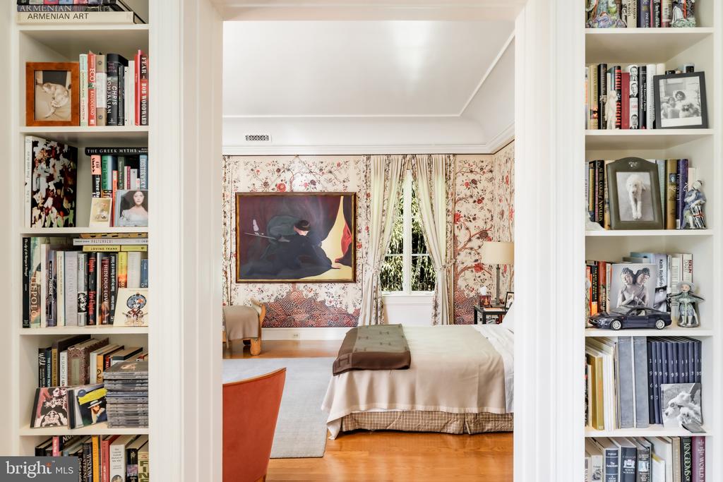 Bedroom with built-in bookshelves, floral wallpaper, and a large framed painting.