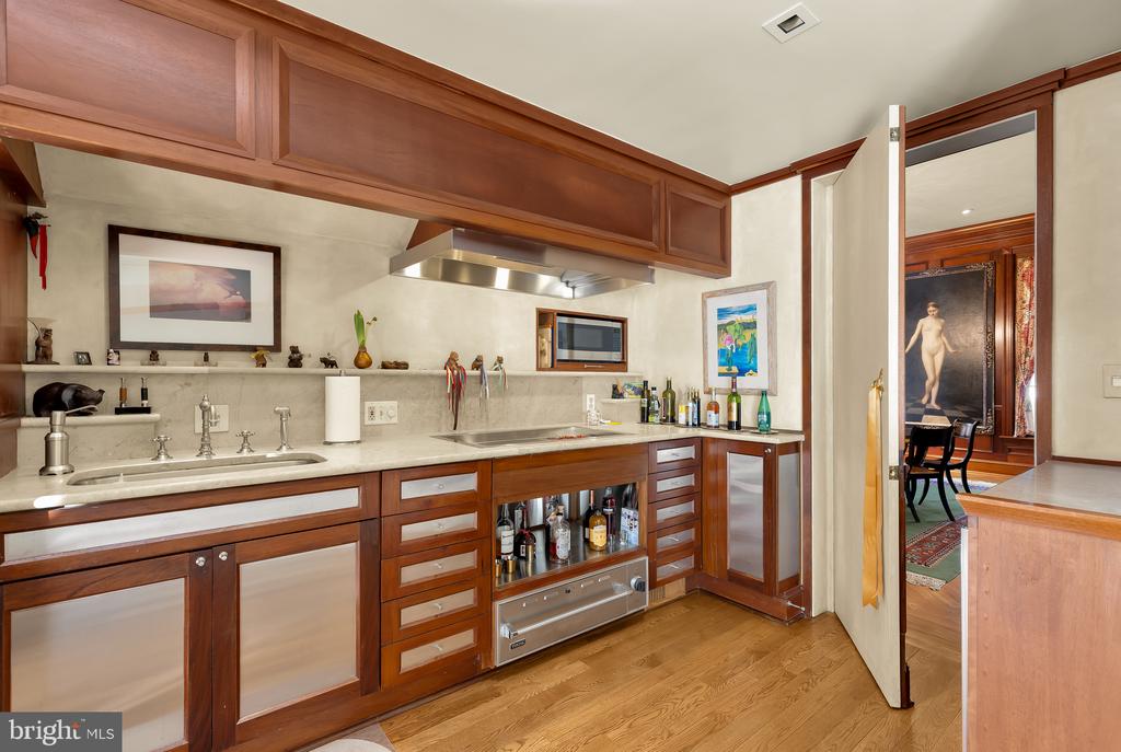 Kitchen with rich wood cabinetry, stone counters, and a stainless steel range hood.