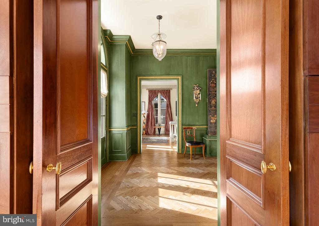 Green foyer with parquet flooring, decorative molding, and open paneled wood doors.