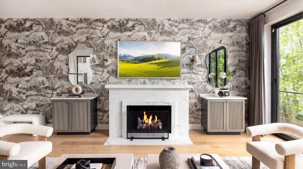 Living room with a marble fireplace, stone-patterned wall, and large windows overlooking greenery.