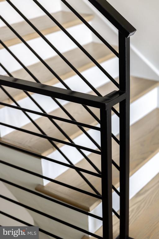 Interior staircase with pale wood treads and a black metal railing.