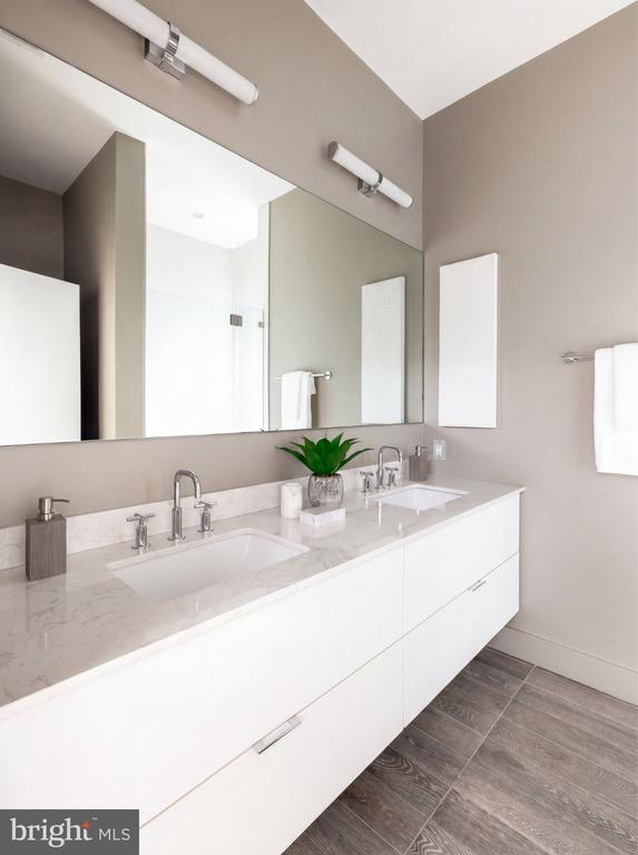 Bright bathroom with a white double vanity, marble-look countertop, large mirror, and dark tile floor.