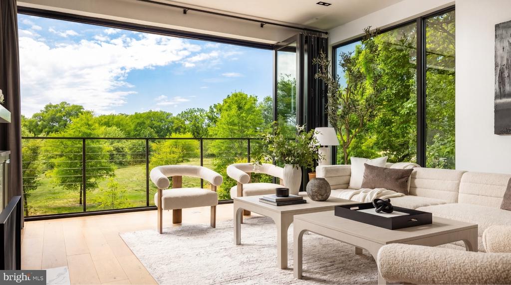 Contemporary living room with a cream sectional and floor-to-ceiling windows overlooking leafy trees.