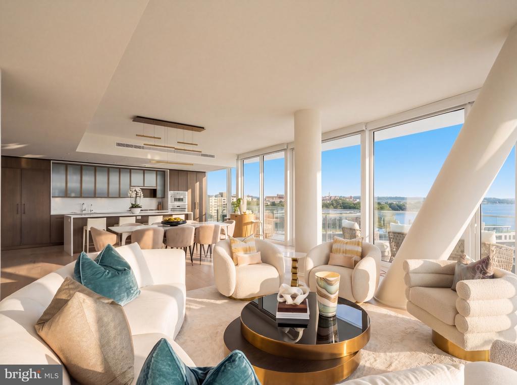 Open-plan high-rise living room with floor-to-ceiling windows overlooking a river and city.