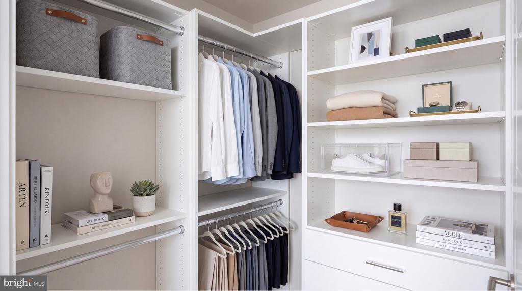 Walk-in closet with white built-in shelves, neatly hung clothes, folded linens, and displayed accessories.