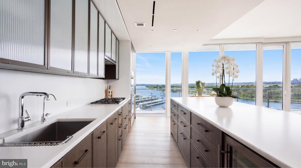 Modern kitchen with a large island and floor-to-ceiling windows overlooking the water.