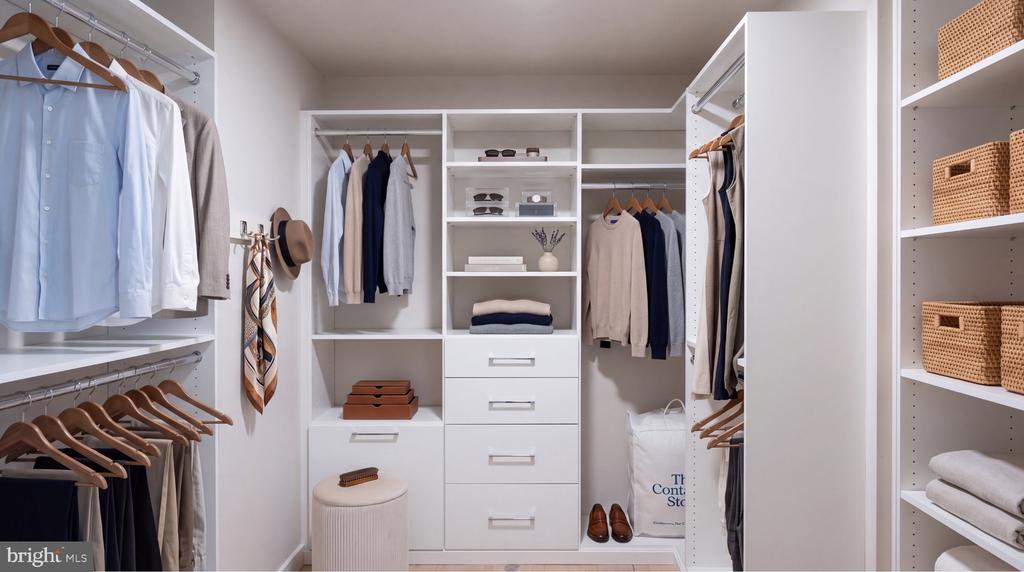 Walk-in closet with white built-ins, organized clothing, woven baskets, and a round upholstered stool.