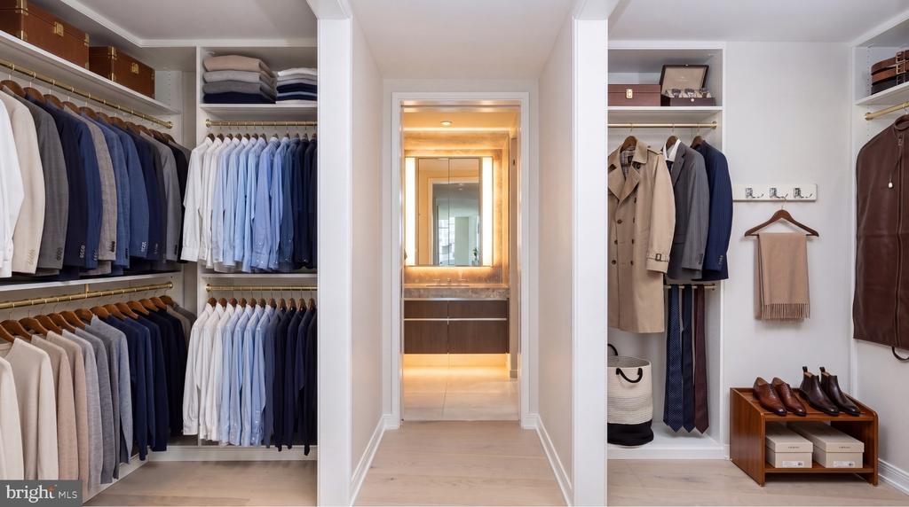 Walk-in closet with built-in racks of clothing and a hallway leading to a bathroom.