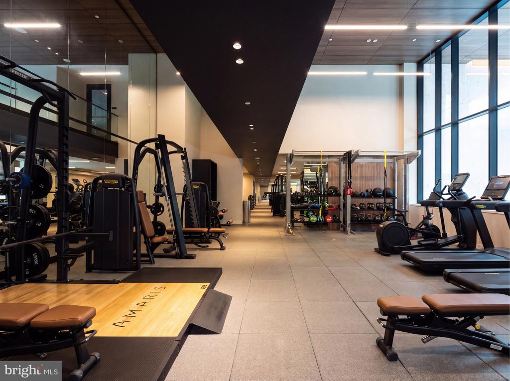 Fitness center with weight machines, free weights, treadmills, and a wooden exercise platform.