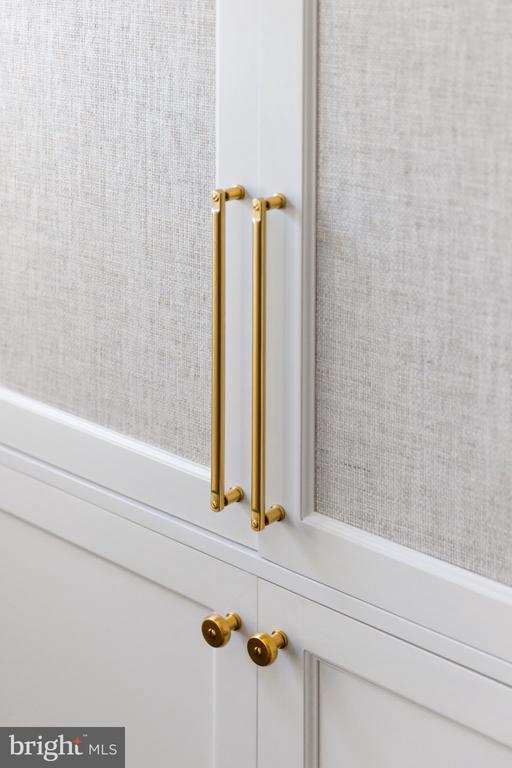 White cabinetry with textured gray panels and long brass handles.