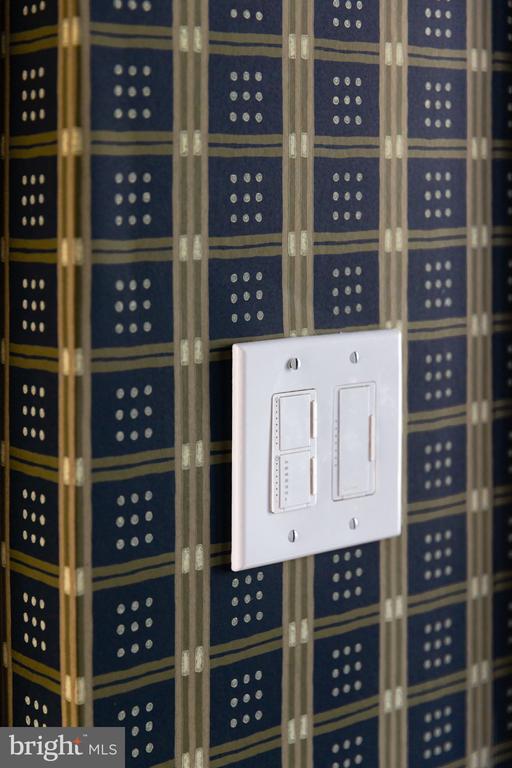 White multi-switch wall plate against dark blue patterned wallpaper.