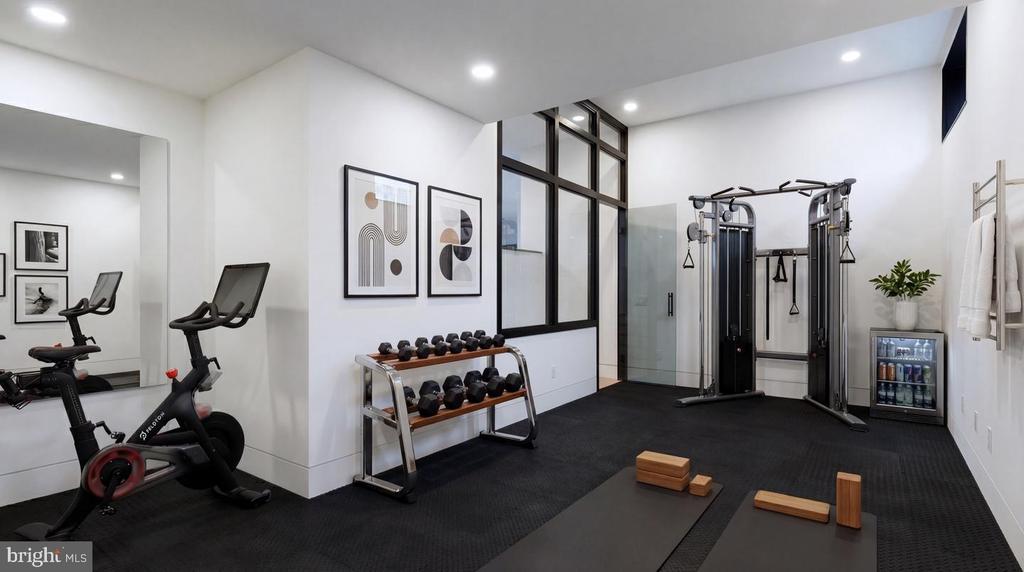 Home gym with a stationary bike, dumbbells, cable machine, and yoga mat.