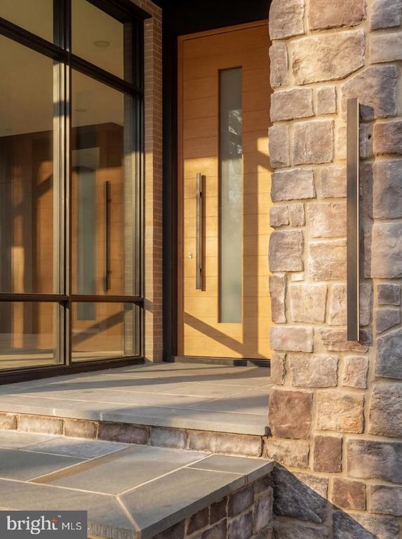 Stone-and-wood front entry with a glazed door, tall windows, and broad stone steps.