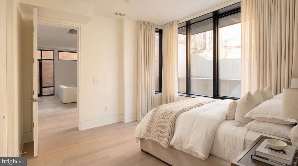 Bright bedroom with white bedding, floor-to-ceiling windows, and an adjoining sitting room.