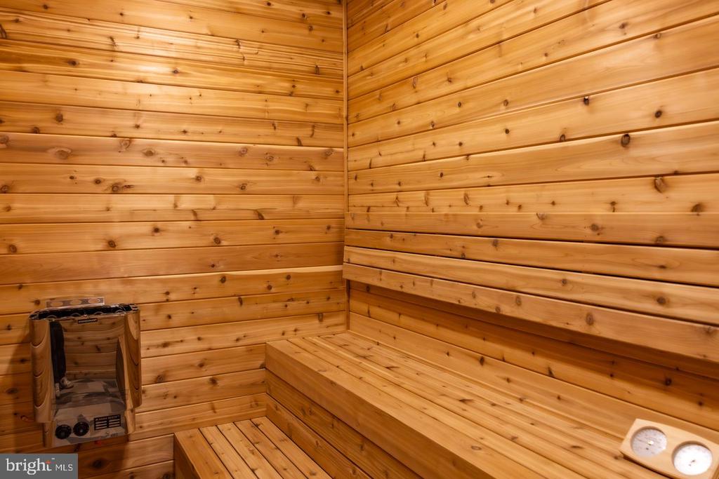 Cedar sauna with tiered benches, a stone heater, and wall gauges.