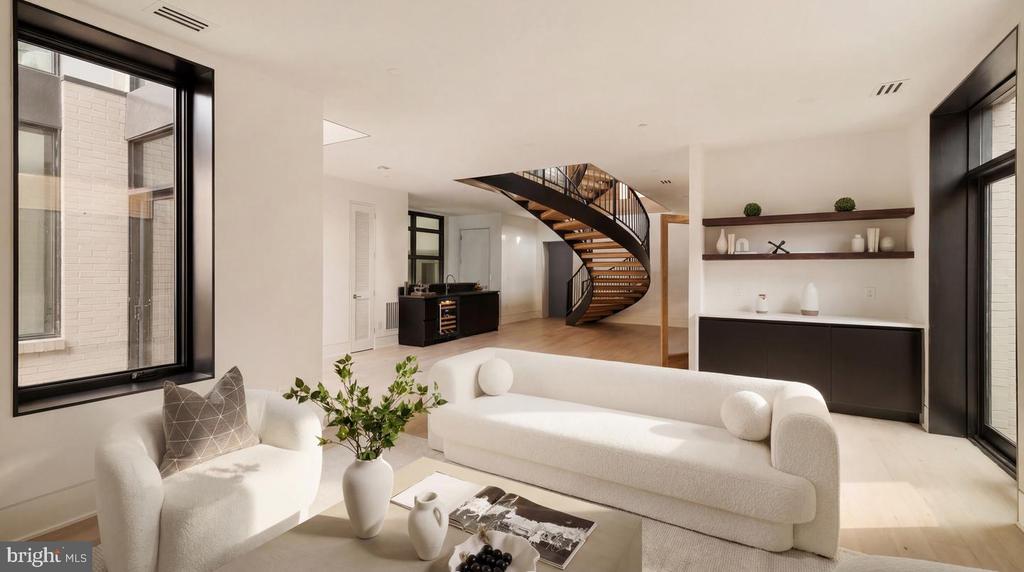 Living room with white sofas, black-framed windows, built-in shelves, and a curved staircase.